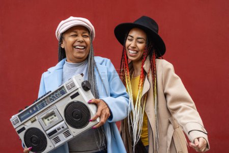 Foto de Feliz madre africana con su hija divirtiéndose bailando y escuchando música con estéreo vintage boombox - Imagen libre de derechos