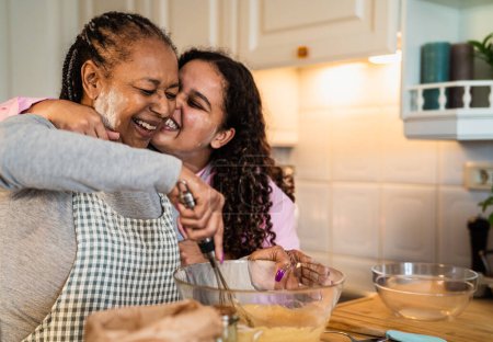 Photo for Happy African mother and daughter having fun preparing a homemade dessert - Royalty Free Image
