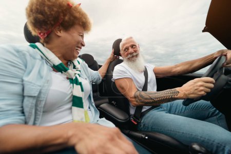Téléchargez les photos : Heureux couple de personnes âgées ayant plaisir à conduire une voiture décapotable pendant un voyage sur la route - Voyage concept de style de vie - en image libre de droit