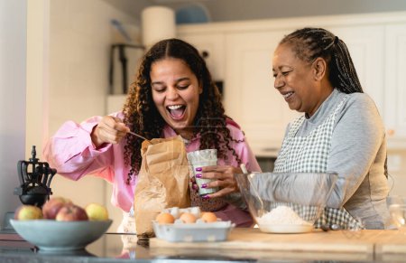Téléchargez les photos : Bonne mère africaine et sa fille s'amusent à préparer un dessert maison - en image libre de droit