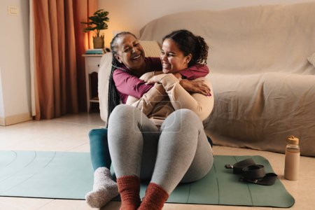 Photo for Happy African mother and daughter having a tender moment while doing pilates at home - Royalty Free Image