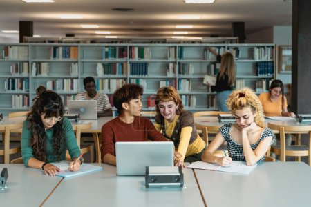 Young university students using laptop and studying with books in library - School education concept