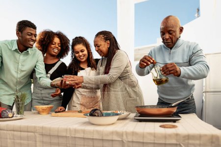 Téléchargez les photos : Happy African family preparing a dinner together on house patio - en image libre de droit