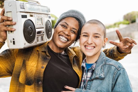 Photo for Happy multiracial girls having fun listening to music with vintage boombox stereo outdoor - Royalty Free Image