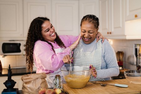 Photo for Happy African mother and daughter having fun preparing a homemade dessert - Royalty Free Image