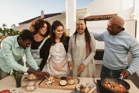 Photo for Happy African family preparing food recipe together on house patio - Royalty Free Image
