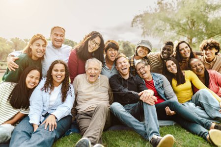 Téléchargez les photos : Heureux gens multigénérationnels s'amuser assis sur l'herbe dans un parc public - en image libre de droit