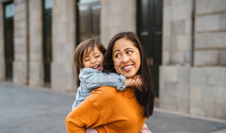 Téléchargez les photos : Bonne mère asiatique du sud-est avec sa fille s'amusant dans le centre-ville - Belle famille en plein air - en image libre de droit