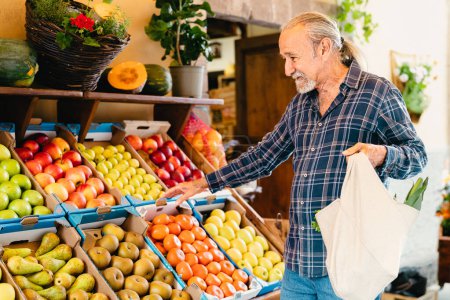 Foto de Hombre mayor feliz comprando frutas frescas en el mercado - Concepto de compra de alimentos - Imagen libre de derechos