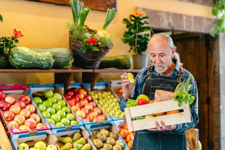 Foto de Verdulero senior que trabaja en el mercado con una caja que contiene frutas y verduras frescas - Concepto de minorista de alimentos - Imagen libre de derechos