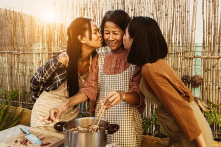 Téléchargez les photos : Mère asiatique du Sud-Est avec ses filles s'amuser à préparer la recette thaïlandaise ensemble à la maison patio - en image libre de droit