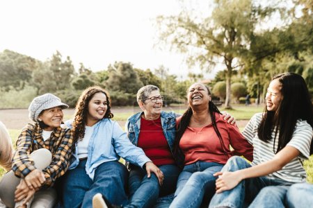 Photo for Happy multi generational group of women with different ethnicities having fun sitting on grass in a public park - Females empowerment concept - Royalty Free Image