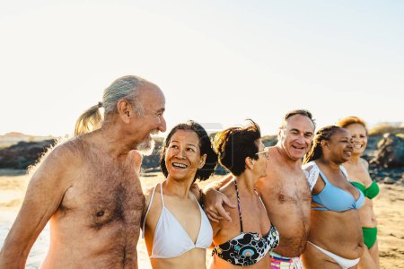 Foto de Felices amigos mayores multirraciales divirtiéndose en la playa durante las vacaciones de verano - Diversos ancianos disfrutando de vacaciones - Imagen libre de derechos