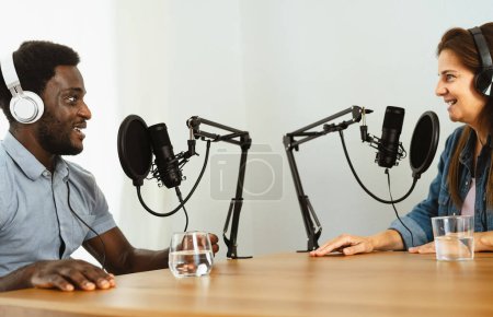 Téléchargez les photos : Heureux amis multiraciaux enregistrant un podcast - Homme et femme s'amusent à travailler ensemble - en image libre de droit