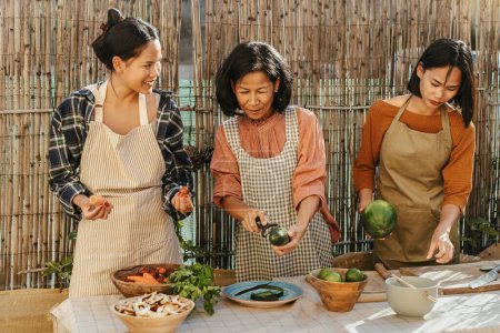 Photo for Happy Southeast Asian family having fun preparing Thai food recipe together at house patio - Royalty Free Image