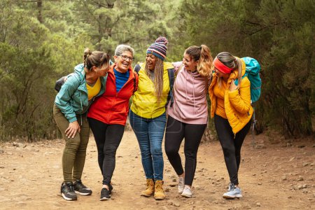 Foto de Mujeres felices con diferentes edades y etnias que se divierten caminando en el bosque - Aventura y viajes concepto de personas - Imagen libre de derechos