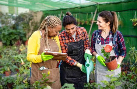 Photo for Happy multiracial women working together in plants and flowers garden shop - Royalty Free Image