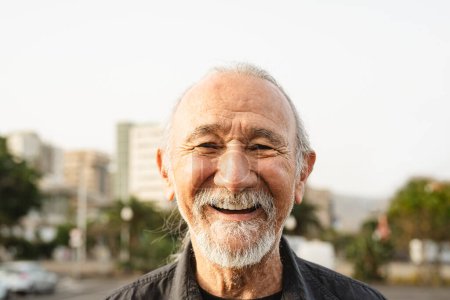 Téléchargez les photos : Heureux homme âgé souriant devant la caméra dans la ville - concept de style de vie des personnes âgées - en image libre de droit