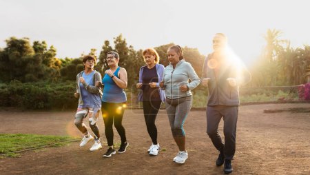 Téléchargez les photos : Groupe d'amis aînés divers jogging ensemble au parc - en image libre de droit