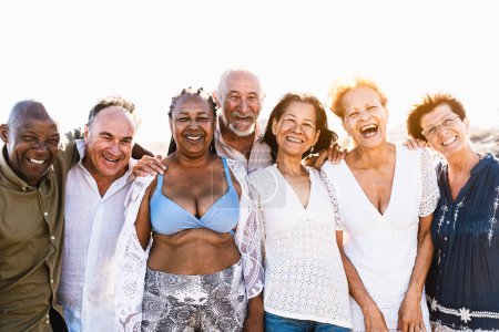 Foto de Feliz multirracial amigos mayores que se divierten sonriendo a la cámara en la playa - Diversos ancianos disfrutando de las vacaciones de verano - Imagen libre de derechos
