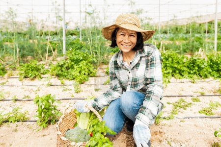 Foto de Feliz mujer del sudeste asiático trabajando dentro de invernadero agrícola - concepto de estilo de vida de los agricultores - Imagen libre de derechos