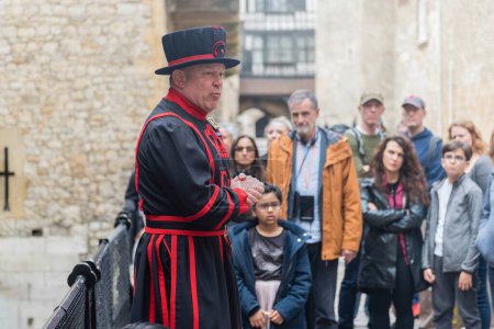 Téléchargez les photos : LONDRES - 13 AVRIL 2022 : Un Yeomen Warder s'entretient avec les visiteurs lors d'une visite de la Tour historique de Londres, Angleterre, Royaume-Uni. Populairement connus comme les Beefeaters sont les gardiens cérémoniels de la Tour de Londres - en image libre de droit