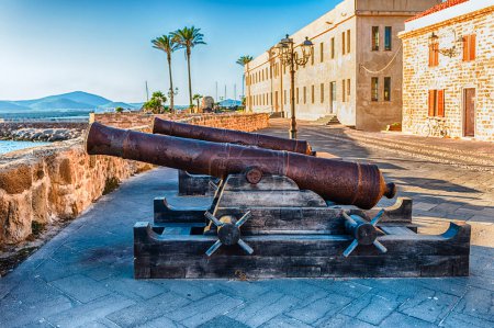 Foto de Antiguos cañones en desuso en las murallas históricas de Alghero, famoso centro y complejo vacacional en el noroeste de Cerdeña, Italia - Imagen libre de derechos