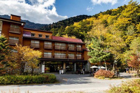 Téléchargez les photos : Kamikochi, Nagano, Japon - Octobre 2022 : Hôtel non identifié pour les touristes dans le parc national de Kamikochi avec un bel arrière-plan de la saison des feuillages d'automne dans les Alpes japonaises. - en image libre de droit