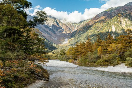 Foto de Hermoso fondo del centro del parque nacional de Kamikochi por montañas de nieve, rocas y ríos Azusa de colinas cubiertas de color de hojas durante la temporada de follaje de otoño. - Imagen libre de derechos