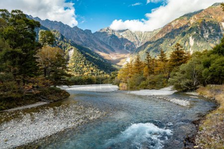 Schöner Hintergrund des Zentrums des Kamikochi-Nationalparks mit Schneebergen, Felsen und Azusa-Flüssen von mit Blättern bedeckten Hügeln, die während der Laubzeit im Herbst ihre Farbe ändern.