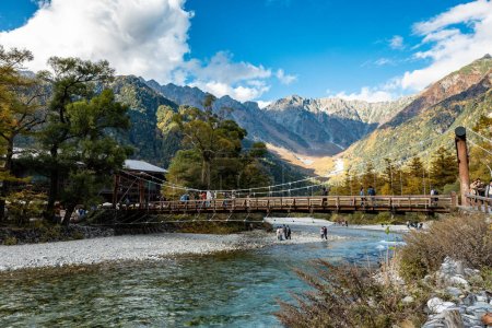 Téléchargez les photos : Kamikochi, Nagano, Japon - Octobre 2022 : Les touristes non identifiés profitent du pont Kappa bashi au centre du parc national de Kamikochi pendant la saison des feuillages d'automne. - en image libre de droit