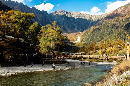 Téléchargez les photos : Kamikochi, Nagano, Japon - Octobre 2022 : Les touristes non identifiés profitent du pont Kappa bashi au centre du parc national de Kamikochi pendant la saison des feuillages d'automne. - en image libre de droit