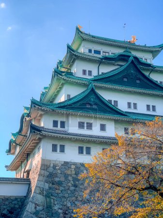 Foto de Film grain Nagoya, Japón Octubre 2022 Castillo de Nagoya con un cielo despejado durante el aderezo de hojas de otoño. Castillo de Nagoya es un punto de referencia en el centro de Chubu de Japón y tiene samurai como el símbolo del castillo. - Imagen libre de derechos
