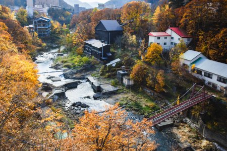 Herbstliche Landschaft des Jozankei Onsen Resorts, ein berühmtes Thermalbad mit Hotels und traditionellem Ryokan, umgeben von herbstlichen Farben.