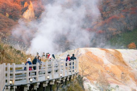 Téléchargez les photos : Shikotsu-Toya National Park, Hokkaido, Japon - Novembre 2023 : Groupe non identifié de touristes Belle vue pendant l'automne et la vapeur montant dans la vallée de l'enfer ou Noboribetsu Jigokudani, Japon - en image libre de droit
