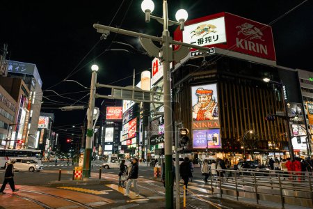 Foto de Susukino Ward, Sapporo, Hokkaido, Japón - Octubre 2023: La intersección de la calle con el signo de Nikka Whisky durante la noche. Varios carteles de neón de colores en todas las áreas de fondo y turistas - Imagen libre de derechos