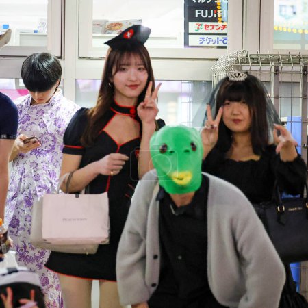 Foto de Sapporo, Japón - Octubre 2023: Noche de Halloween con una multitud de adolescentes japoneses vestidos con disfraces de Halloween y maquillaje caminando por el sendero en el área de la cruz de Susukino. - Imagen libre de derechos