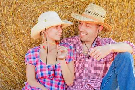 Foto de Happy couple on the field with bales harvest in autumn - Imagen libre de derechos