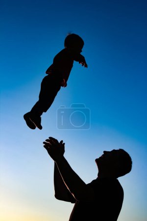 Téléchargez les photos : A parent with a child playing on the beach silhouette - en image libre de droit