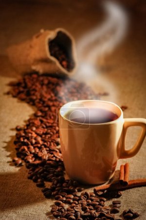 Foto de Taza de café y granos de café sobre una mesa de madera y fondo de saco, tono de color vintage - Imagen libre de derechos