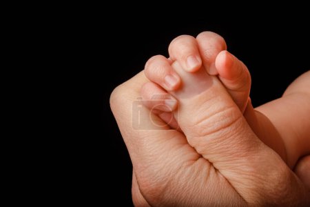 Téléchargez les photos : Beautiful baby lies on the hands of the parent handles legs background - en image libre de droit