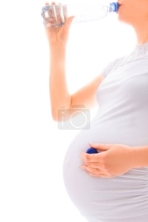 Foto de Hermosa joven embarazada sobre un fondo blanco con una botella - Imagen libre de derechos