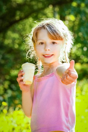 Photo for Child eating ice cream in the park on the background - Royalty Free Image