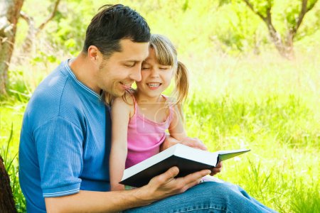 Téléchargez les photos : Jeune père avec une petite fille lisant la Bible - en image libre de droit
