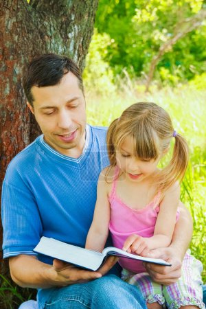 Photo for Young father with a small daughter reading the Bible - Royalty Free Image