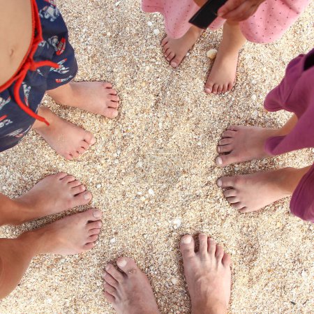 Foto de Piernas de toda la hermosa familia en la arena cerca del fondo del mar - Imagen libre de derechos