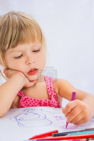 Téléchargez les photos : Enfant heureux dessine sur un fond blanc - en image libre de droit
