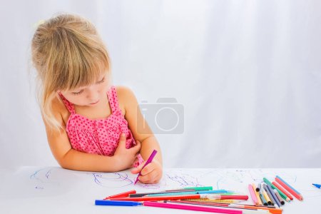 Téléchargez les photos : Enfant heureux dessine sur un fond blanc - en image libre de droit