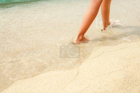 Photo for Beach travel - woman relaxing walking on a sandy beach leaving footprints in the sand. Close up detail of female feet on golden sand at a beach in Greece. Background. - Royalty Free Image