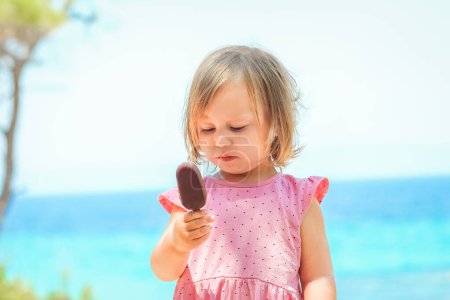 Téléchargez les photos : Joyeux enfant fille avec de la crème glacée au bord de la mer dans la nature dans le voyage du parc - en image libre de droit